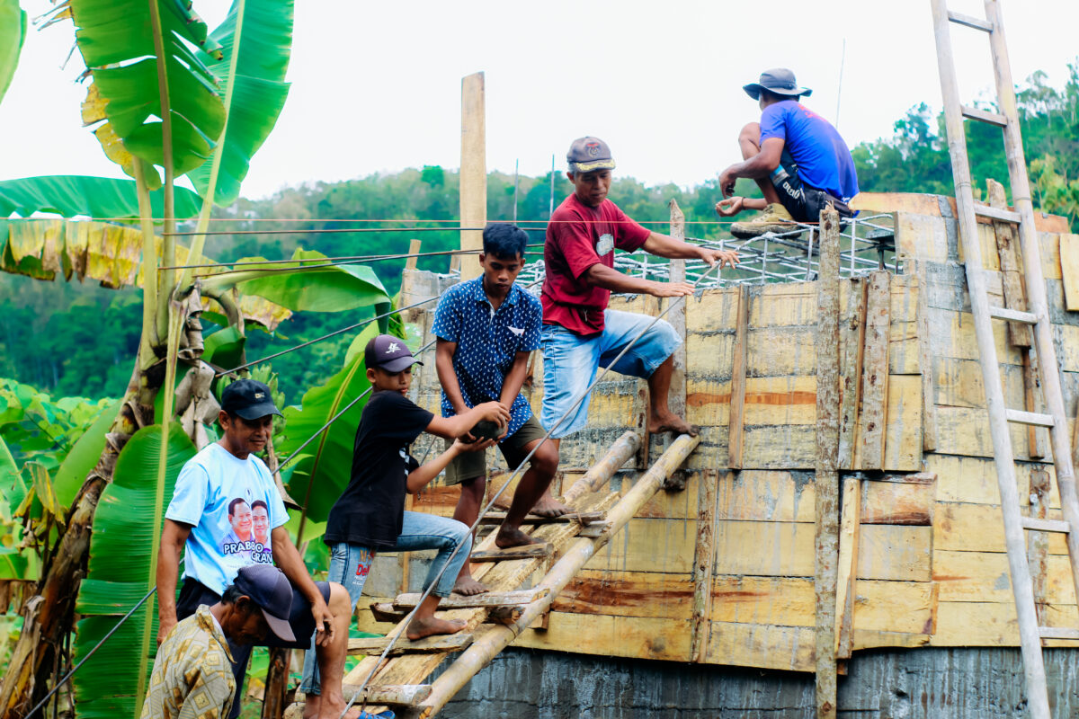 Warga dan relawan bergotong royong memasang rangka jembatan di daerah pedesaan