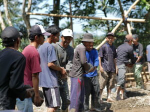 Warga dan relawan bergotong royong memasang rangka jembatan di daerah pedesaan